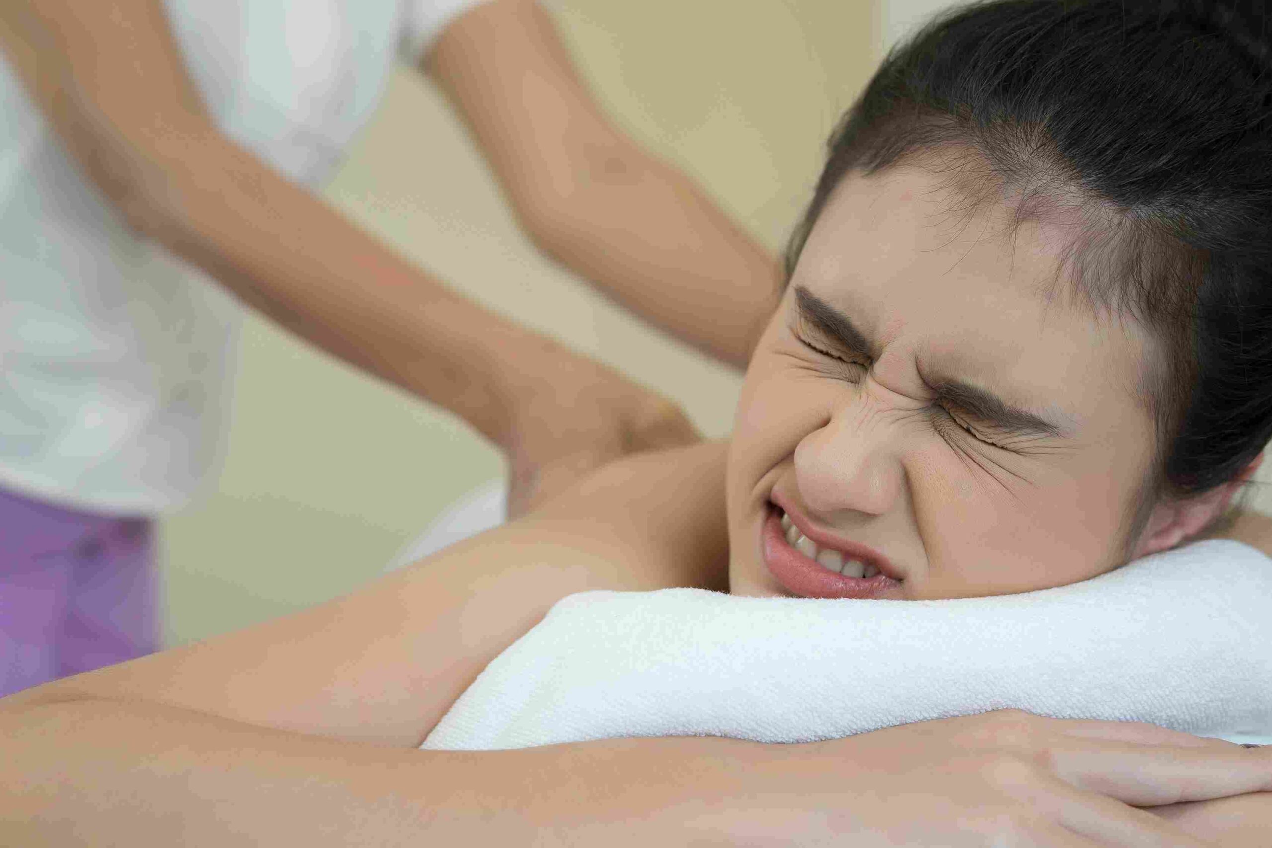 Wanita meringis saat menjalani body massage untuk membantu meredakan otot tegang.